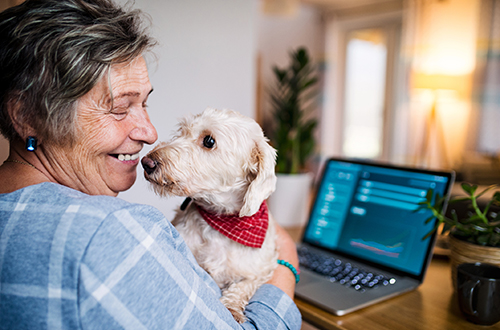 Lady holding her dog on her desk, smiling
